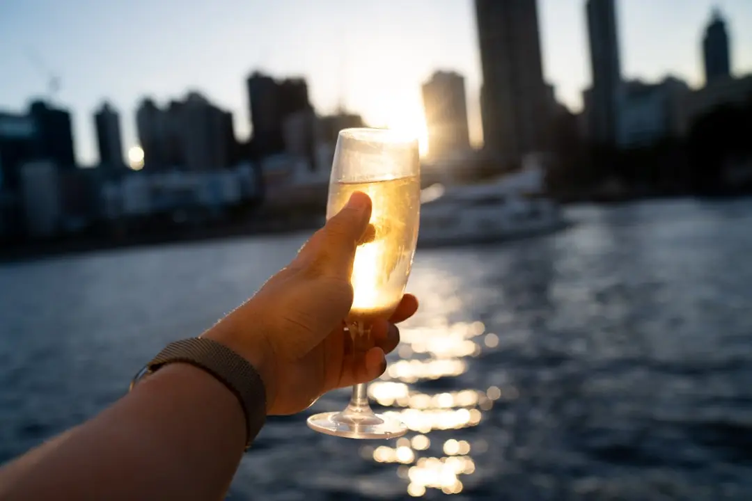 Hand holding champagne flute with city skyline at sunset