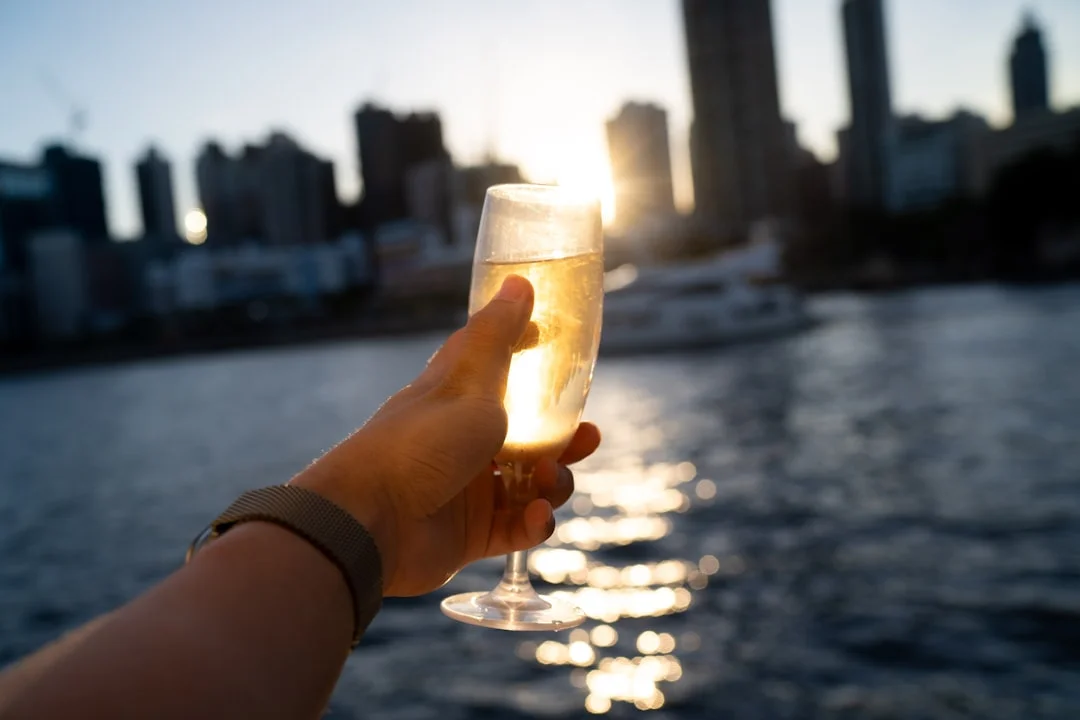 Hand holding champagne flute with city skyline at sunset