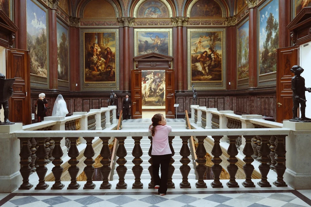 A person looks at paintings in a grand hall.