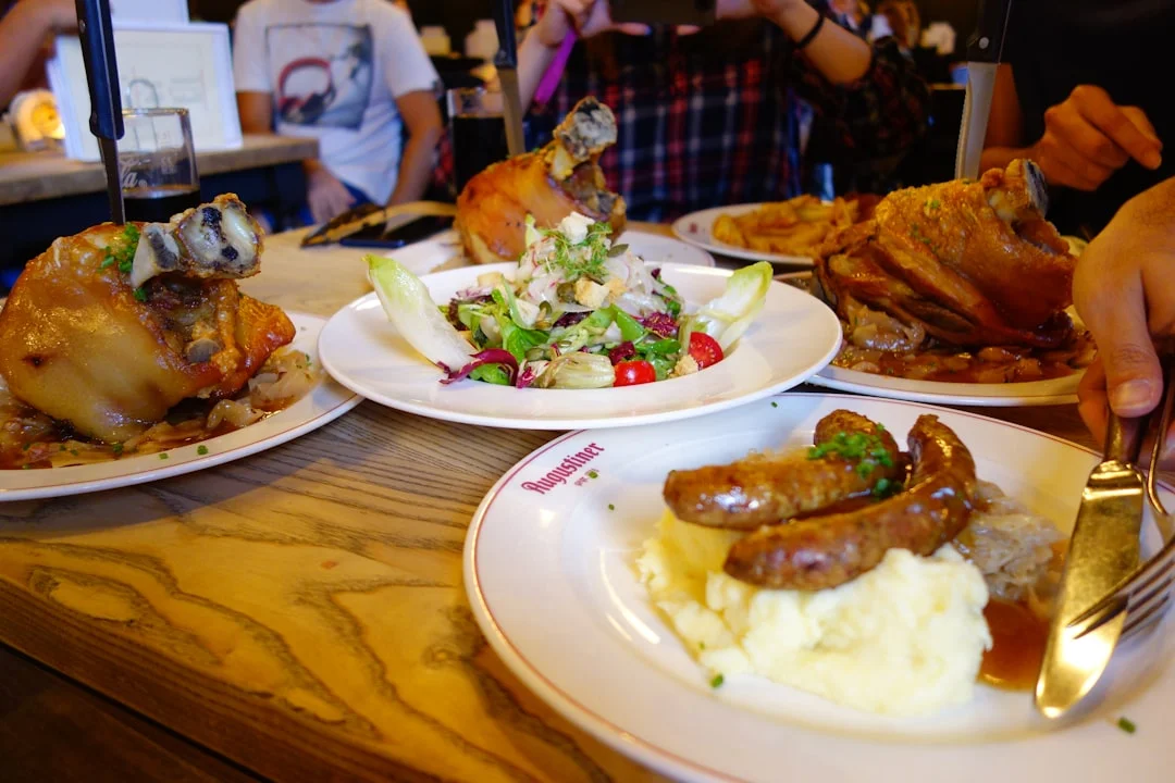 Table laden with roasted pork, sausages, mashed potatoes, and salad